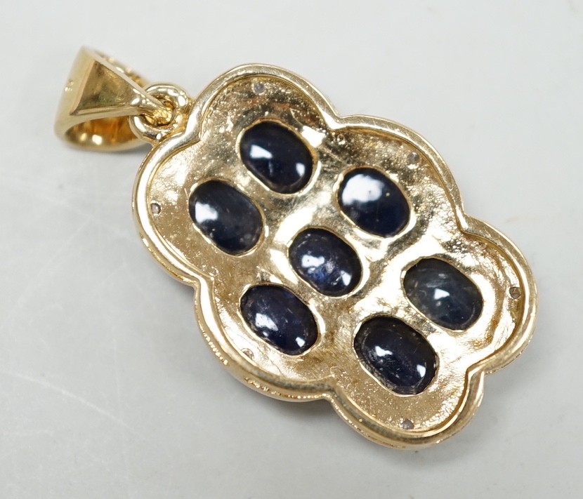 A modern 9ct gold, cabochon sapphire cluster and diamond chip set shaped oval pendant, overall 37mm, gross weight 8.4 grams.